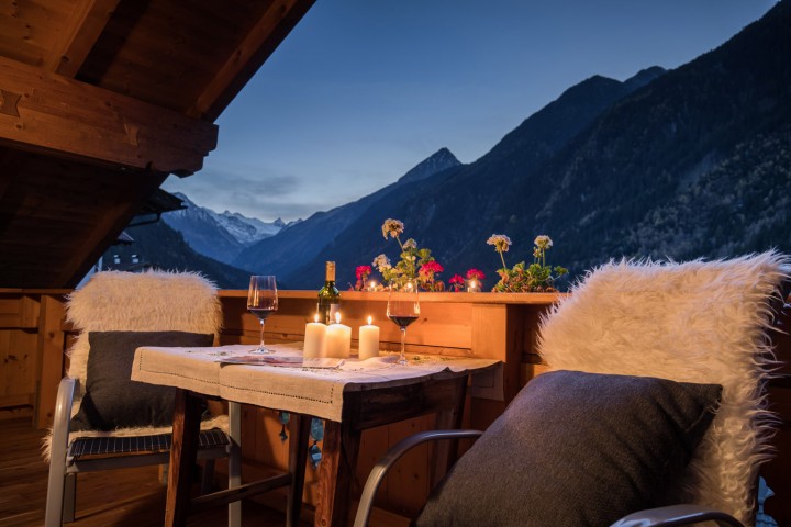 A table decorated with two chairs on a balcony and a lit candle creates an inviting atmosphere.