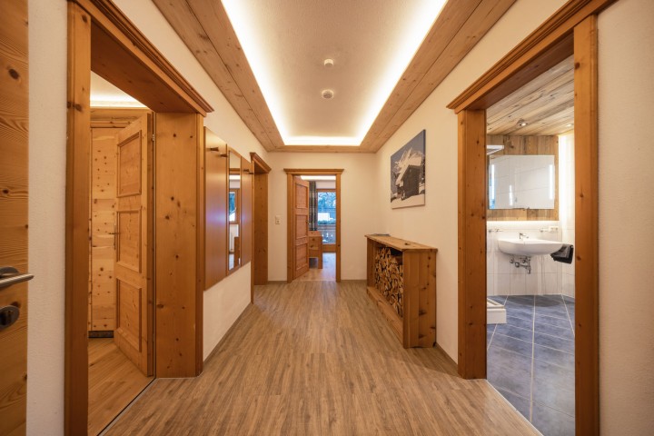  Ein Flur mit Holzböden, der zu einem Badezimmer führt, das eine einladende Atmosphäre ausstrahlt.