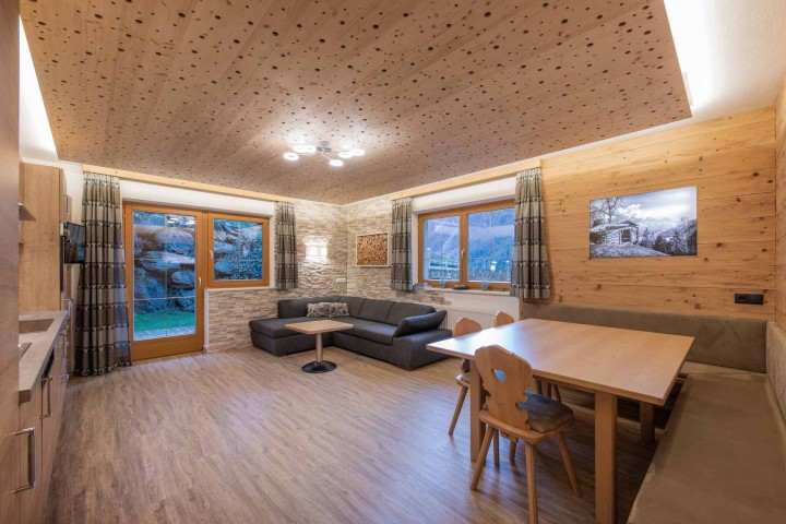 Cozy living room with a sofa, table and chairs, ideal for social gatherings. A fitted kitchen completes the room.