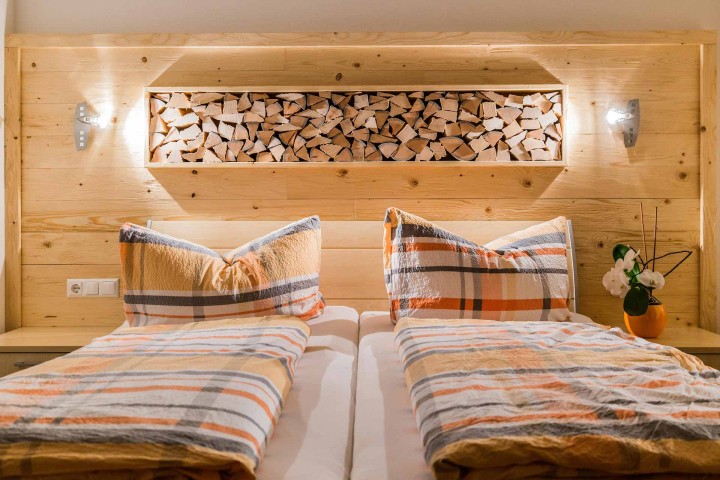 Cozy bedroom with two beds, furnished with orange and white comforters, creates a warm and inviting ambience. Wood decor elements.