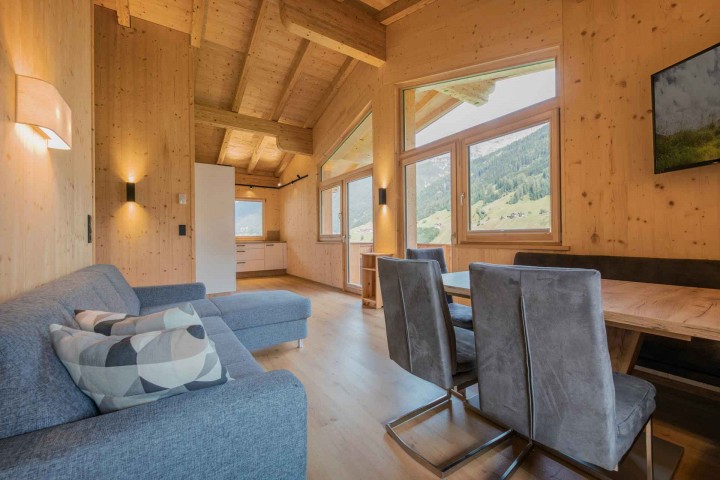 Living and dining area in a modern wood look with a view of the kitchen and the mountain landscape