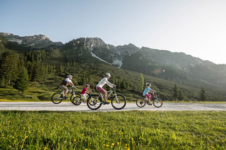 A family cycling along a picturesque mountain path in the Stubai Valley, Tyrol