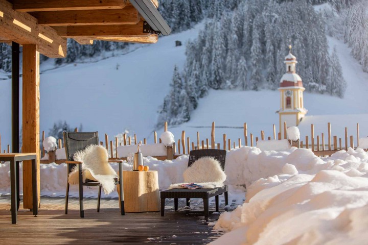 Cozy wooden deck with chairs, surrounded by an impressive mountain landscape in the background