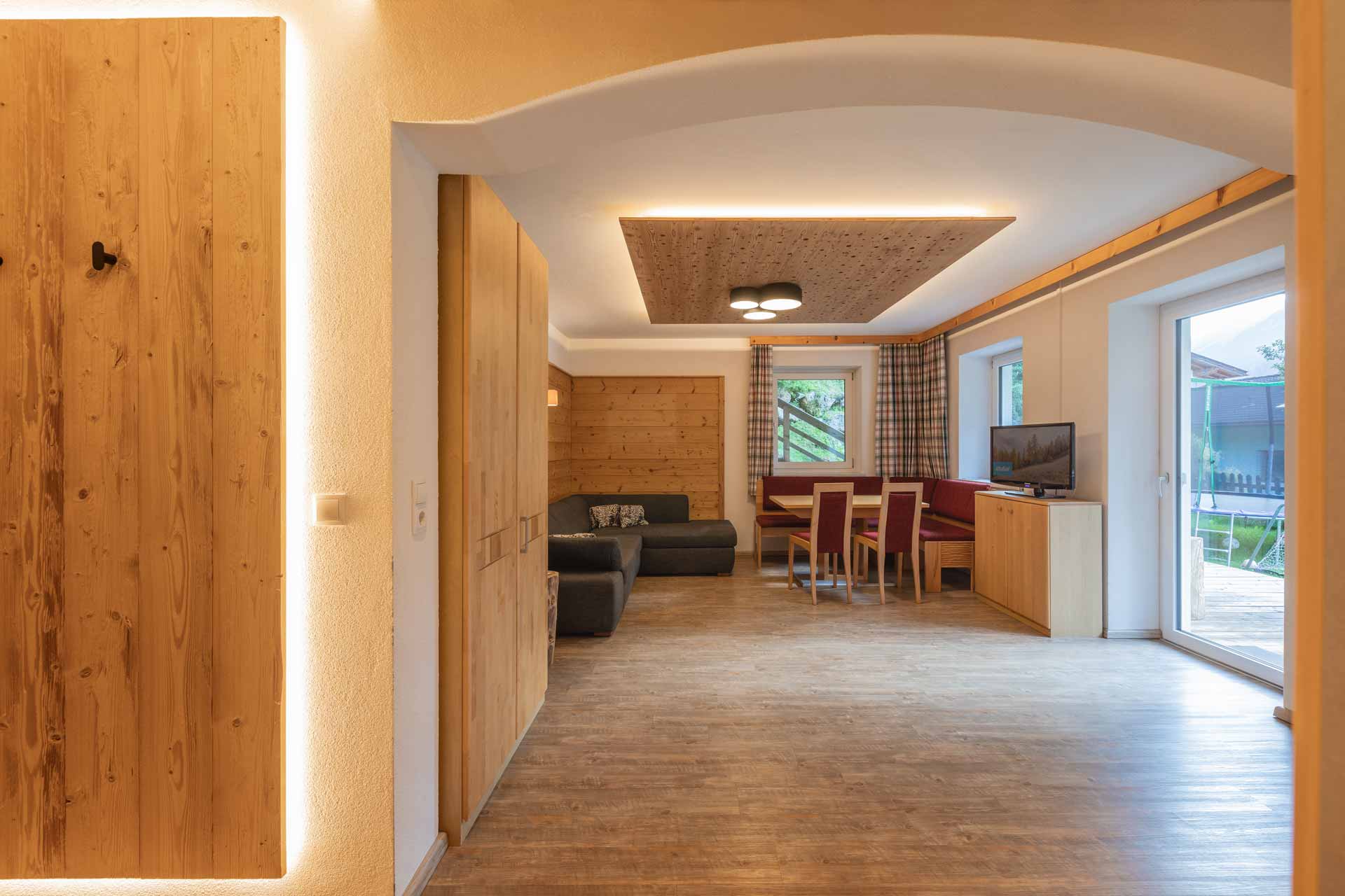 <h3>Ferienwohnung Gletscherglühen</h3> Ferienwohnung Gletscherglühen: Wohnzimmer in Ferienwohnung Gletscherglühen mit warmen Holzverkleidungen und komfortablem Sofa. Unterkunft im Stubaital, Tirol.