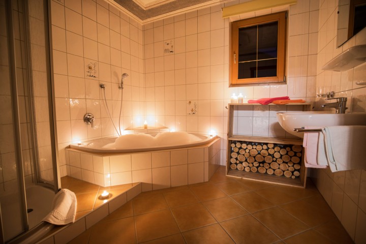 Bathroom decorated with candles with shower, bubble bath in a bathtub and washbasin