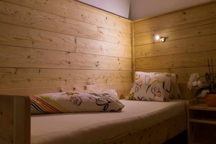 Comfortable single bed behind a wooden wall