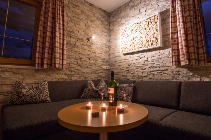 A couch with a table and a bottle of wine that creates a cozy atmosphere for relaxing and socializing.