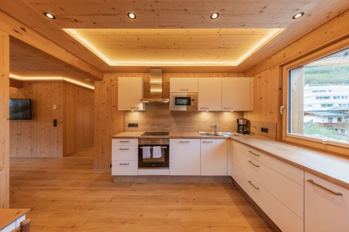 Wohn- und Essbereich mit direktem Zugang zur Küche. Wände und Decken sind mit Holz verkleidet