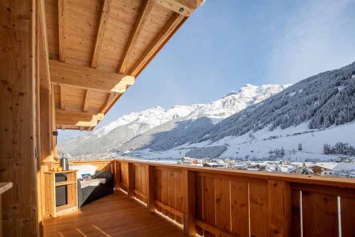 View of the snow-covered Stubai Valley from the balcony with seating area